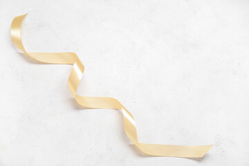 Golden satin ribbon on white grunge background
