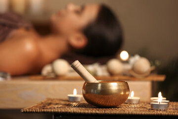 Tibetan singing bowl with aroma candles on table in spa salon