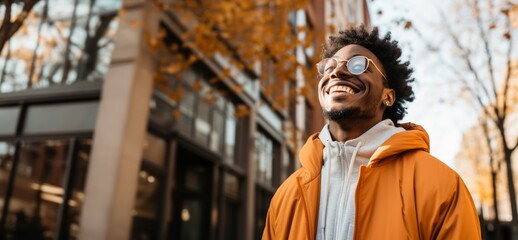 black person with glasses and afro hair looking up with yellow jacket and white sweatshirt laughing and very happy.