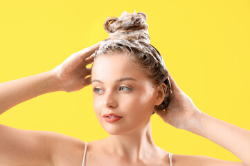 Young woman washing hair on yellow background, closeup