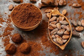 Bowl with cocoa powder, candies and beans on black background