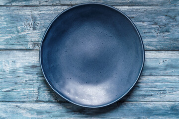 Empty blue plate on old shabby wooden table - 653008089