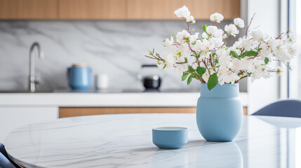 Vase with fresh spring flowers on dinning table on the background of modern kitchen in Scandinavian interior style. Light white blue colors. 