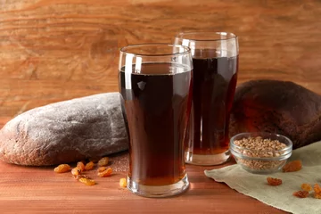  Glasses of tasty kvass, bread, raisins and wheat grains on wooden background © Pixel-Shot