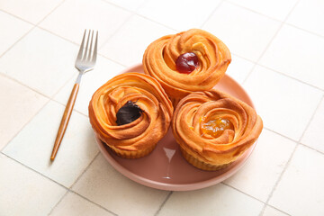 Plate of tasty cruffins with chocolate and jam on white tile background