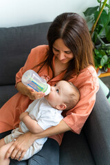 Baby bottle-feeding in mother's arms