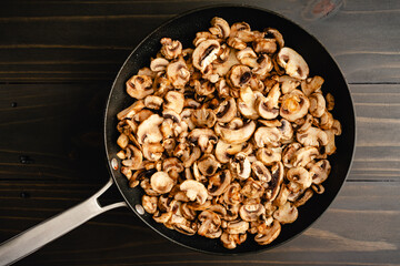 Sliced Button Mushrooms in a Large Non-stick Saute Pan: Slices of white mushrooms cooking melted butter in a large non-stick skillet