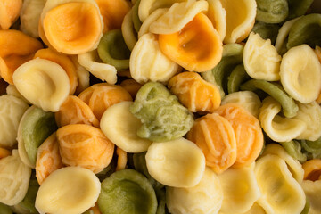 Close-up Overhead View of Cooked Tricolor Orecchiette Pasta: Cooked and drained yellow, orange, and green orecchiette pasta viewed from above