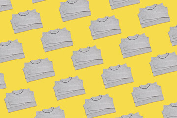 Knitted grey color pullover pattern on yellow background.