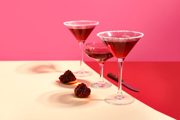 Glasses of Cosmopolitan cocktail with pomegranate on colorful background