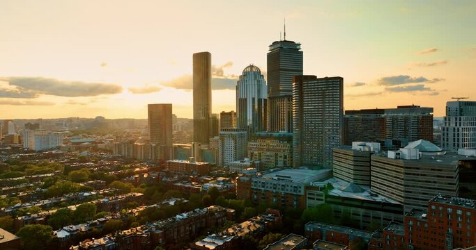 Sun setting above the beautiful Boston, Massachusetts, USA. Drone footage above the low-rise blocks of flats distancing from skyscrapers.