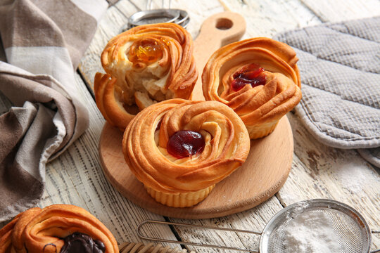 Board of tasty cruffins with jam on white wooden background