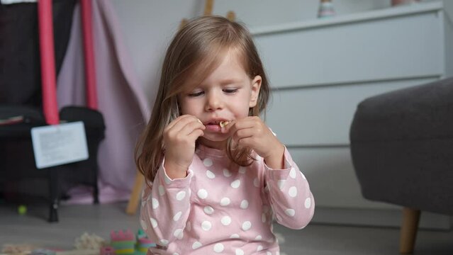 One girl caucasian toddler child eat macaroni pasta at home with hands
