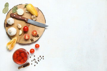 Jar of pickled tomatoes and wooden board with different spices on white background