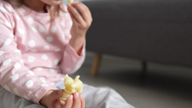 One girl caucasian toddler child eat macaroni pasta at home with hands