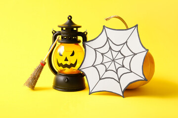 Halloween lantern, web and broom on yellow background