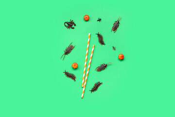 Halloween composition with candy bugs, straws and pumpkins on green background