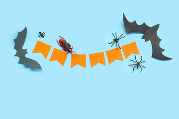 Halloween composition with candy bugs, bats and garland on blue background