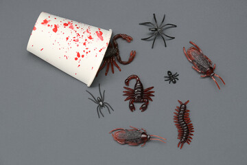 Halloween composition with bloodstained bugs and candy bugs on dark grey background