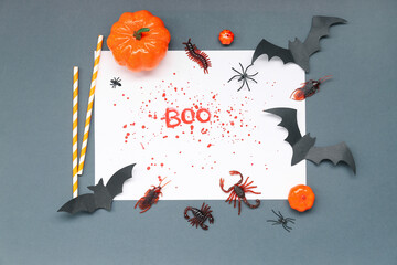 Halloween composition with bats, candy bugs, pumpkins and word BOO made from blood on dark grey...