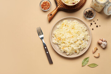 Plates of tasty sauerkraut with spices and garlic on beige background