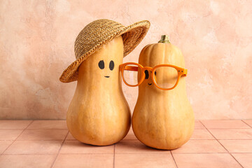 Cute pumpkins with drawn faces on beige tiled table