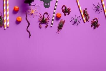 Halloween composition with candy bugs, pumpkins and straws on purple background