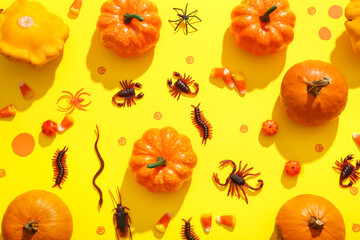 Halloween composition with candy bugs and pumpkins on yellow background