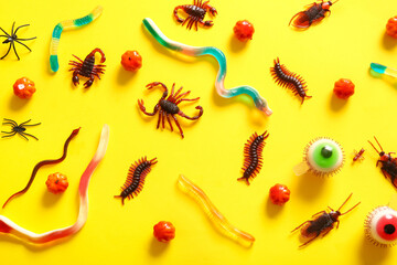 Halloween composition with candy bugs and eyeballs on yellow background