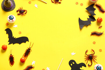 Halloween composition with candy bugs, bats and pumpkins on yellow background