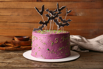 Tasty cake decorated for Halloween on wooden background