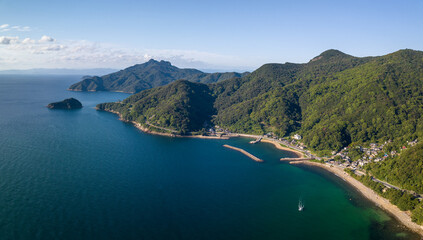 Aerial view of small coastal beach town by mountains on Shodo Island - 653020221