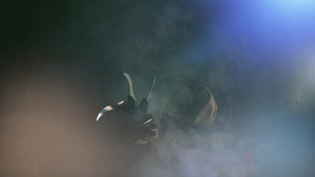 man is like a serial killer freddy with a glove c sharp knives in the mist, background for Halloween