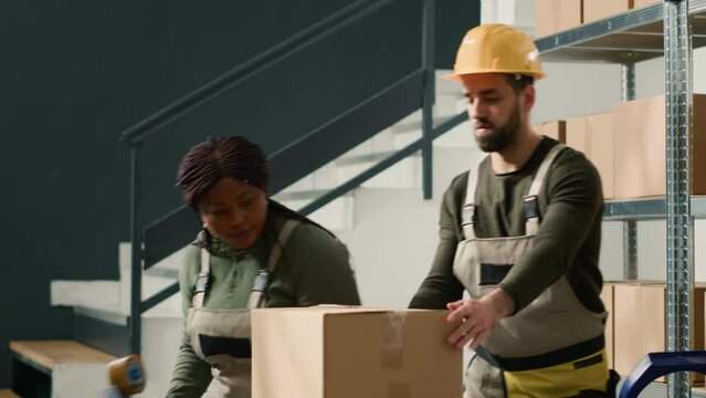 Warehouse colleagues sealing cardboard box package ready to be shipped to customers. Staff members in storage facility securing parcels to avoid issues during delivery