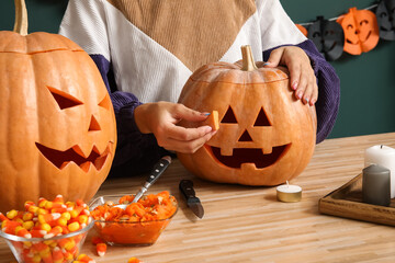 Woman with carved Halloween pumpkin at wooden table
