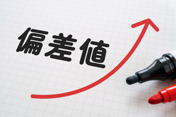 偏差値と上向の矢印が書かれたノートとマーカー