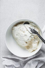 Strained Greek yogurt in a white ceramic bowl, process of making Greek yogurt, strained thick yogurt in white mixing bowl