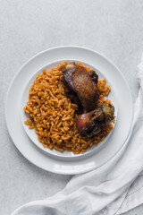 Jollof rice and fried chicken on a white plate, homemade nigerian jollof rice on a plate, overhead view of authentic homemade west african jollof rice
