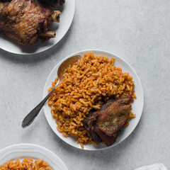 Jollof rice and fried chicken on a white plate, homemade nigerian jollof rice on a plate, overhead view of authentic homemade west african jollof rice