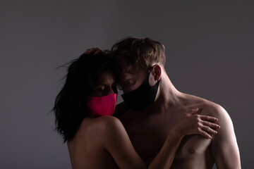 Young loving couple wearing face masks, hugging and staring at each other's eyes, virus spread...