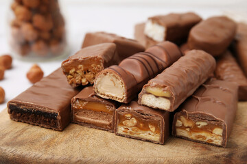 Pieces of different tasty chocolate bars on wooden board, closeup