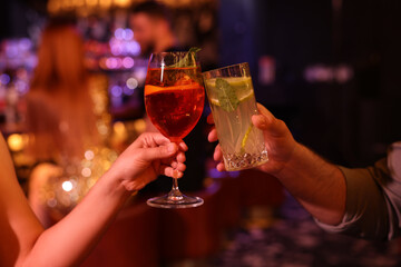 People clinking glasses with fresh cocktails in bar, closeup