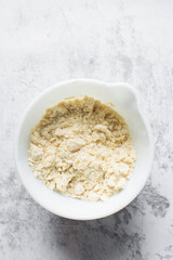 butter and flour being mixed together in a white bowl, butter and flour mixed into rough pastry, butter and flour being used to make cookie dough or pie dough, process of making cut out sugar cookies