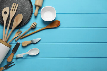 Set of different kitchen utensils on light blue wooden table, flat lay. Space for text
