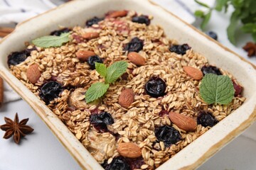 Tasty baked oatmeal with berries and almonds in baking tray on white table, closeup