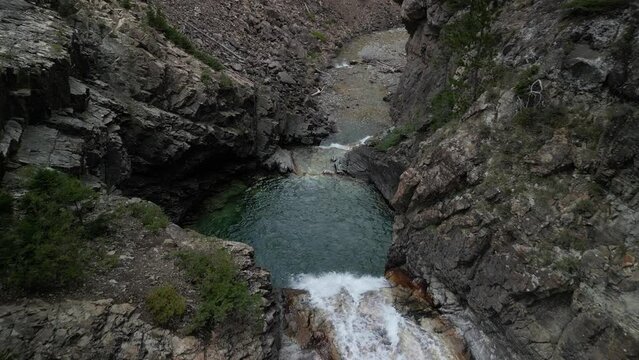 Aerial tilt down on blue water of Devils Punchbowl waterfall in Crested Butte Colorado