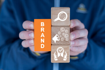 Hands holding colorful blcoks with icons and word: BRAND. Brand marketing and management, branding or rebranding concept.