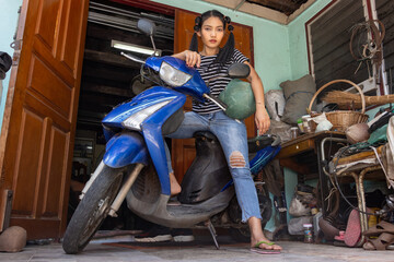 A young woman is standing by a motorcycle parked in front of the entrance to a house - Powered by Adobe