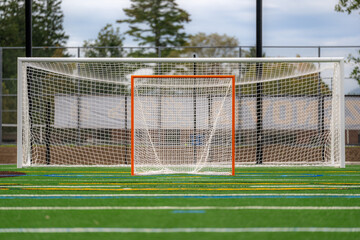 Photo of a lacrosse goal on a empty green synthetic turf field.	