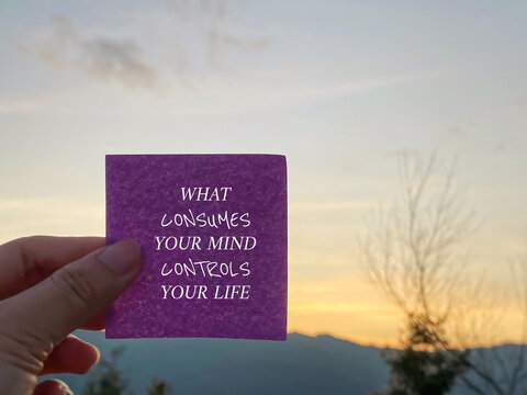 Motivational inspirational quote. What consumes your mind, controls your life on paper with blurry nature background.